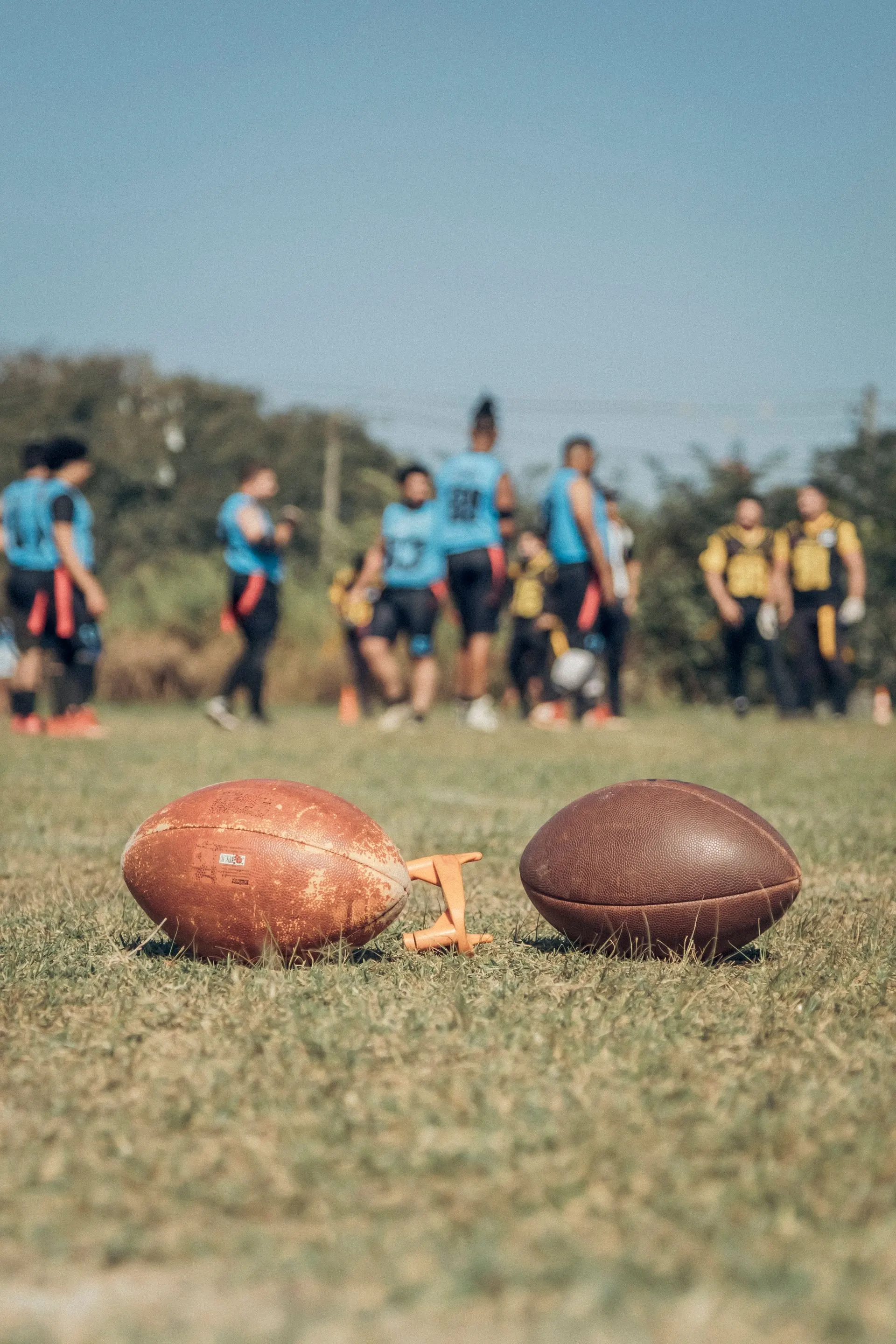 Zwei Footballs im Gras, dahinter Spieler
