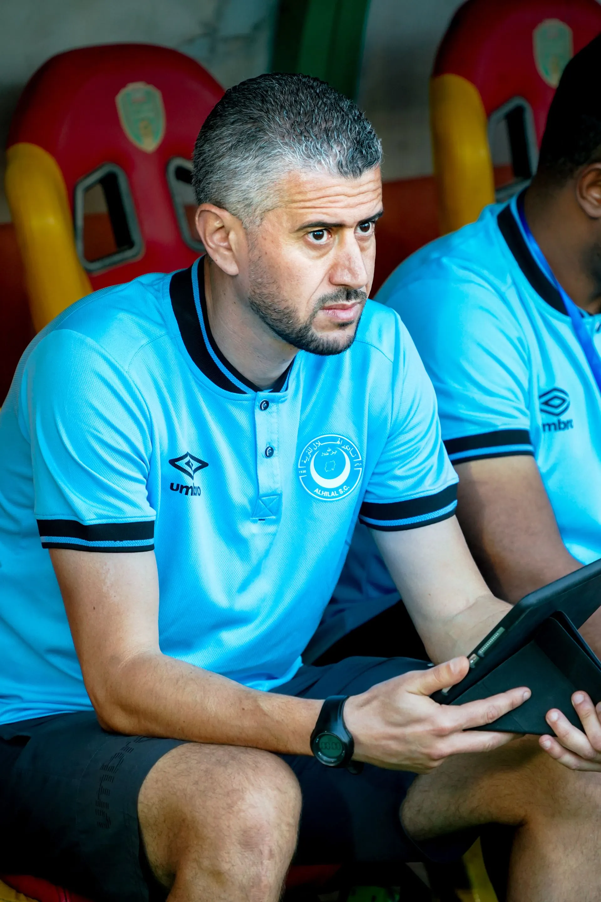 Trainer sieht auf der Bank auf ein Tablet